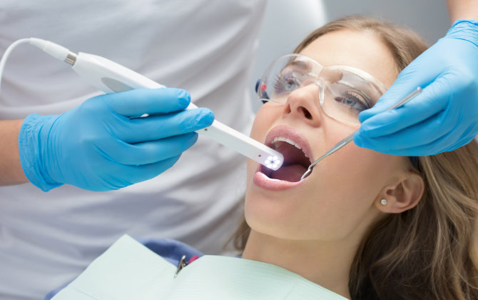 A woman is getting her teeth cleaned by a dentist.