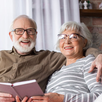 elderly couple embrace on the couch and smiles friendly