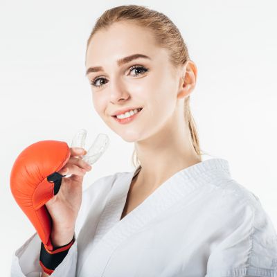 smiling female karate fighter holding mouthguard